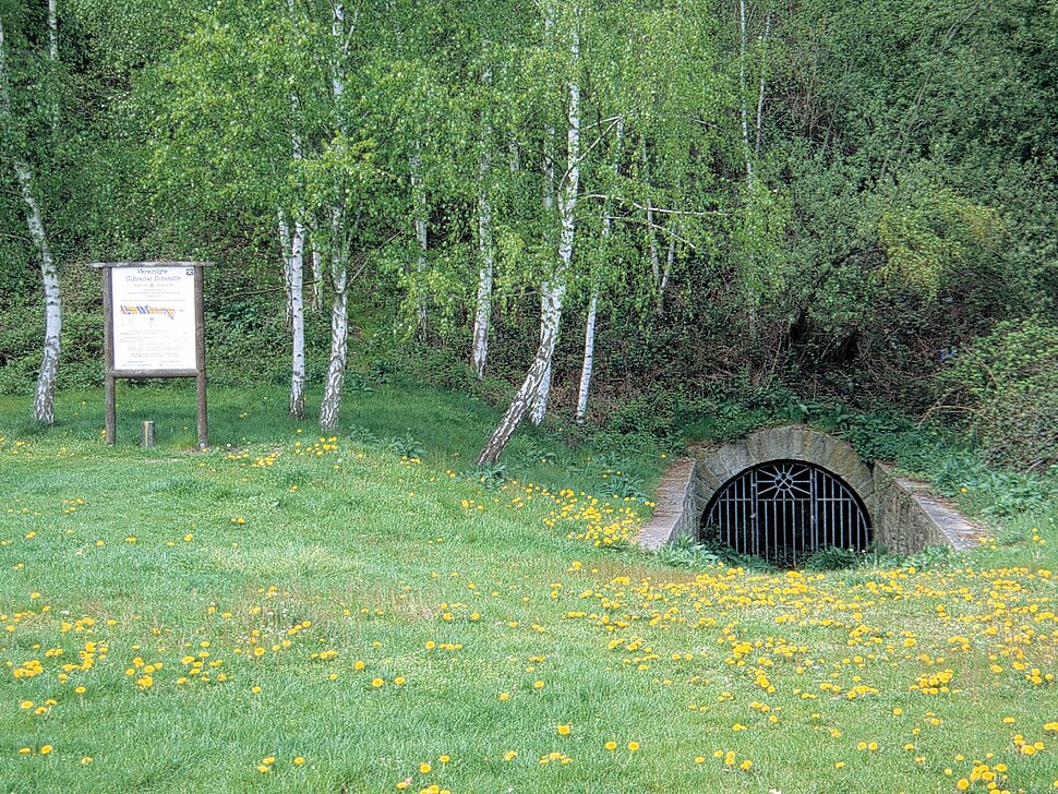 Stolleneingang auf Wiese mit Infotafel