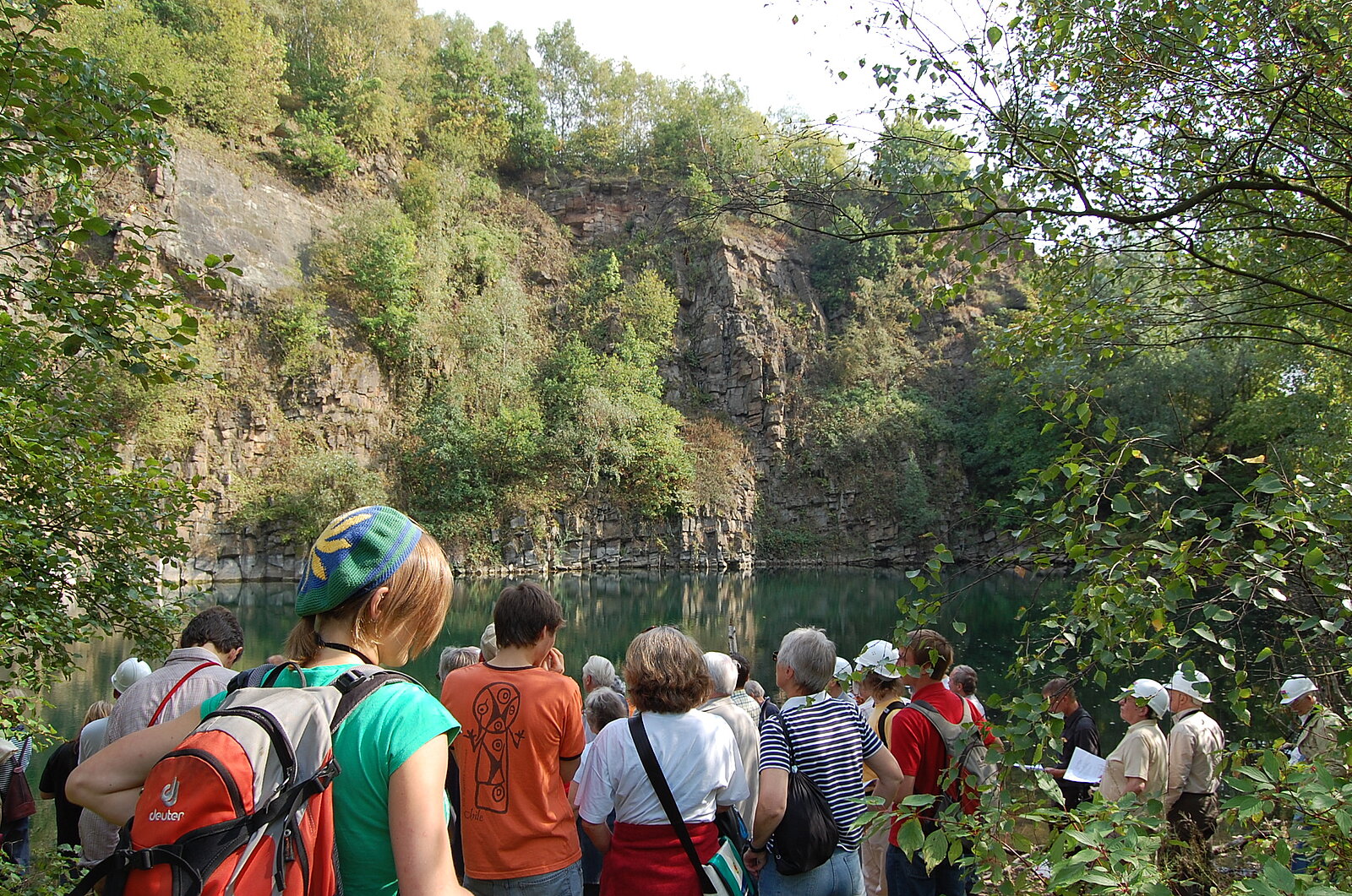 Gruppe von Exkursionsteilnehmern im Sommer vor See und Felswand
