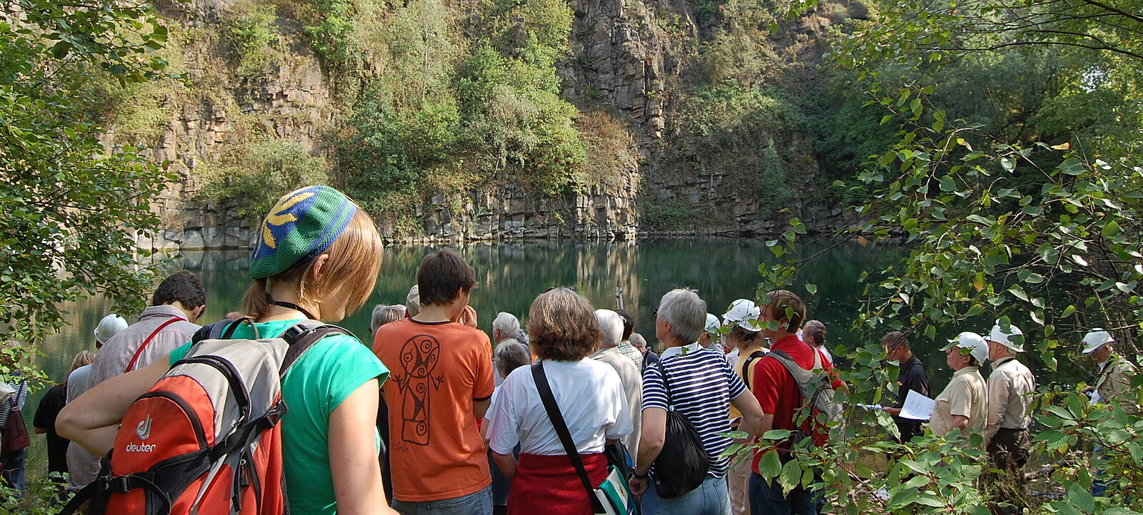 Gruppe von Exkursionsteilnehmern im Sommer vor See und Felswand