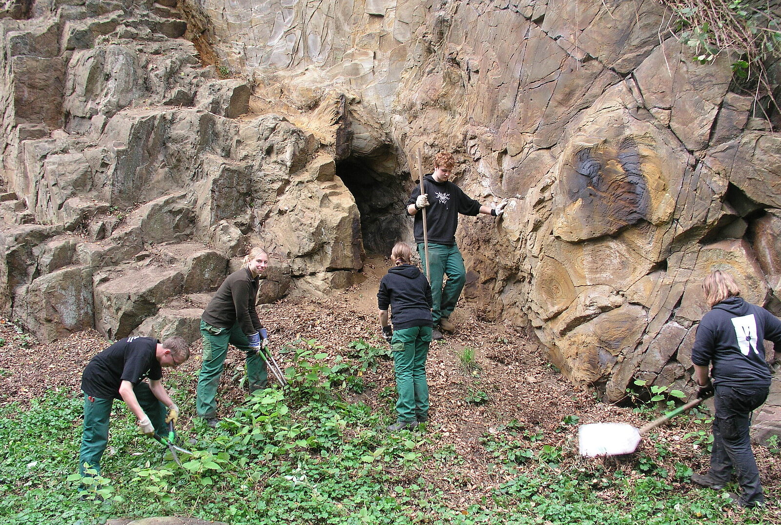 Fünf junge Leute in Arbeitskleidung und Gartenwerkzeug