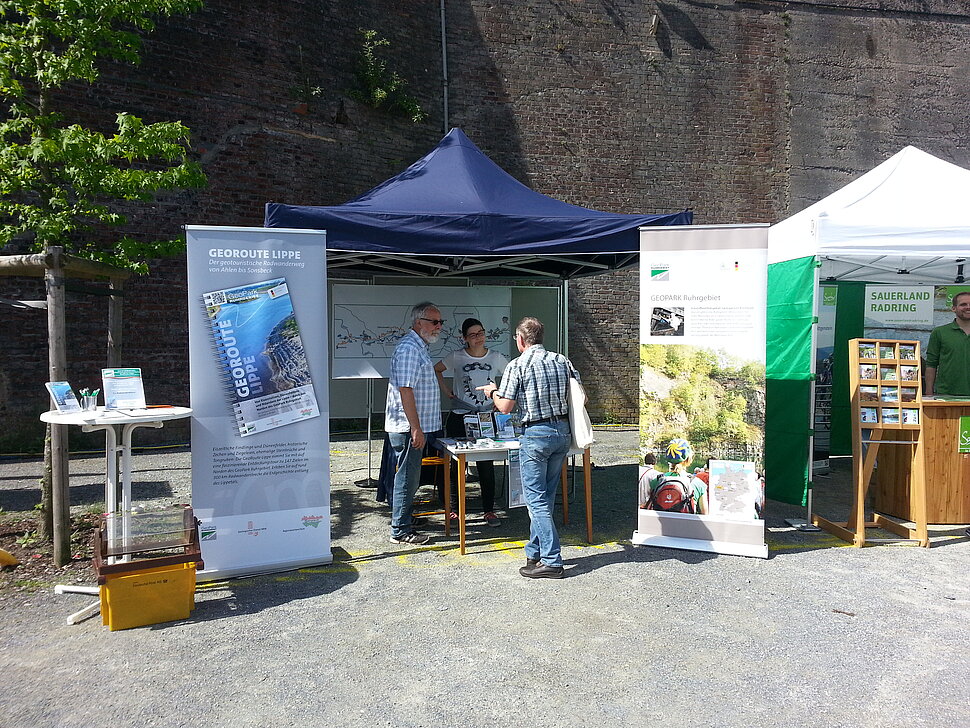 Infostand mit Zelten, Rollups und drei Leuten