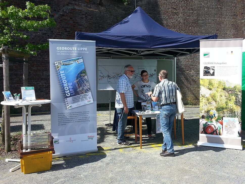 Infostand mit Zelten, Rollups und drei Leuten