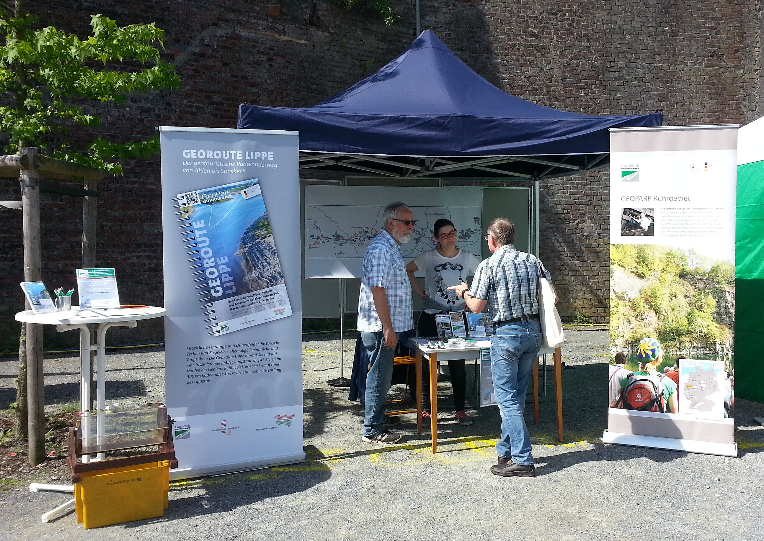 Infostand mit Zelten, Rollups und drei Leuten