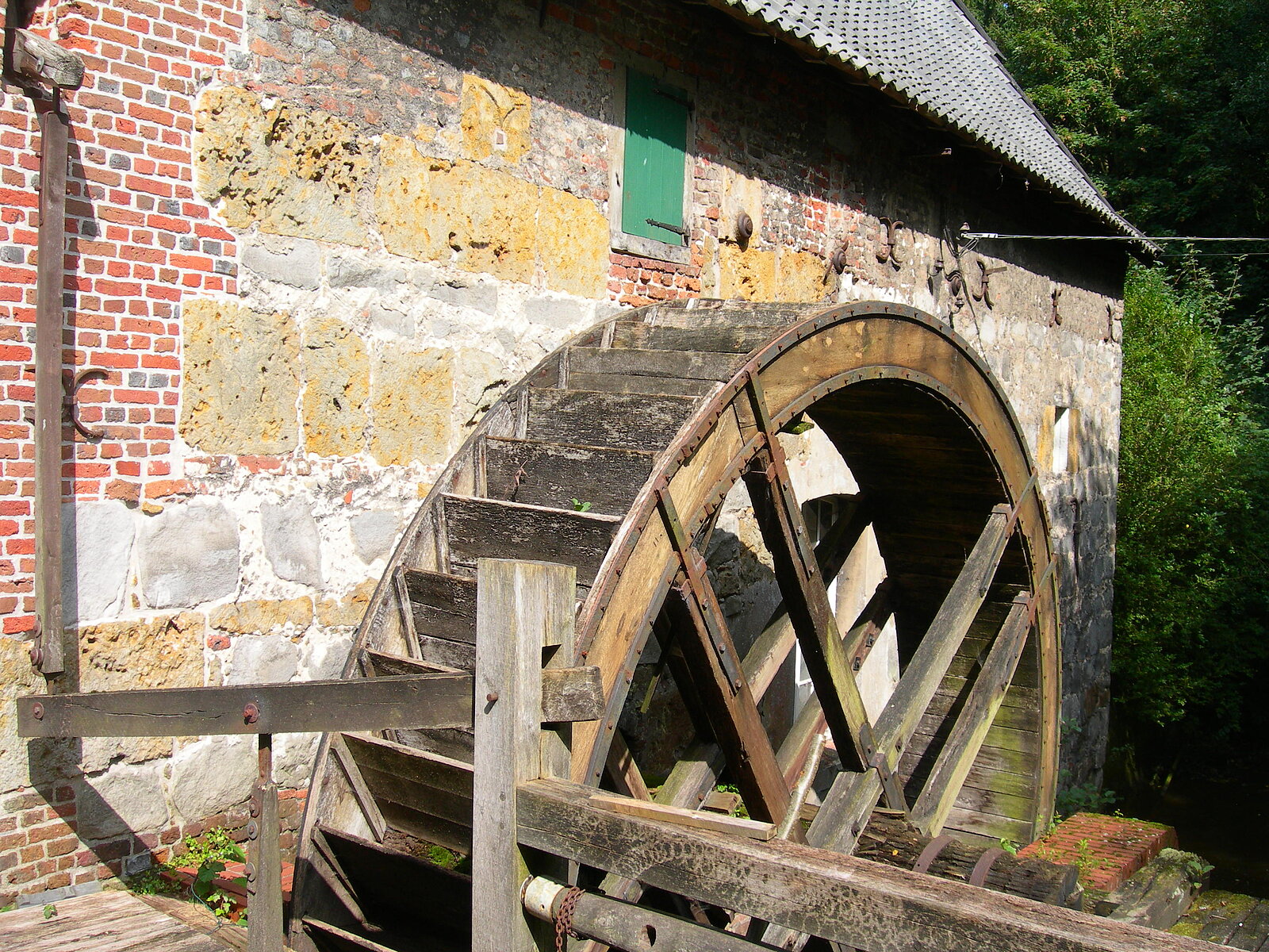 Mühlrad vor Mauer aus dehr unterschiedlichen Steinen