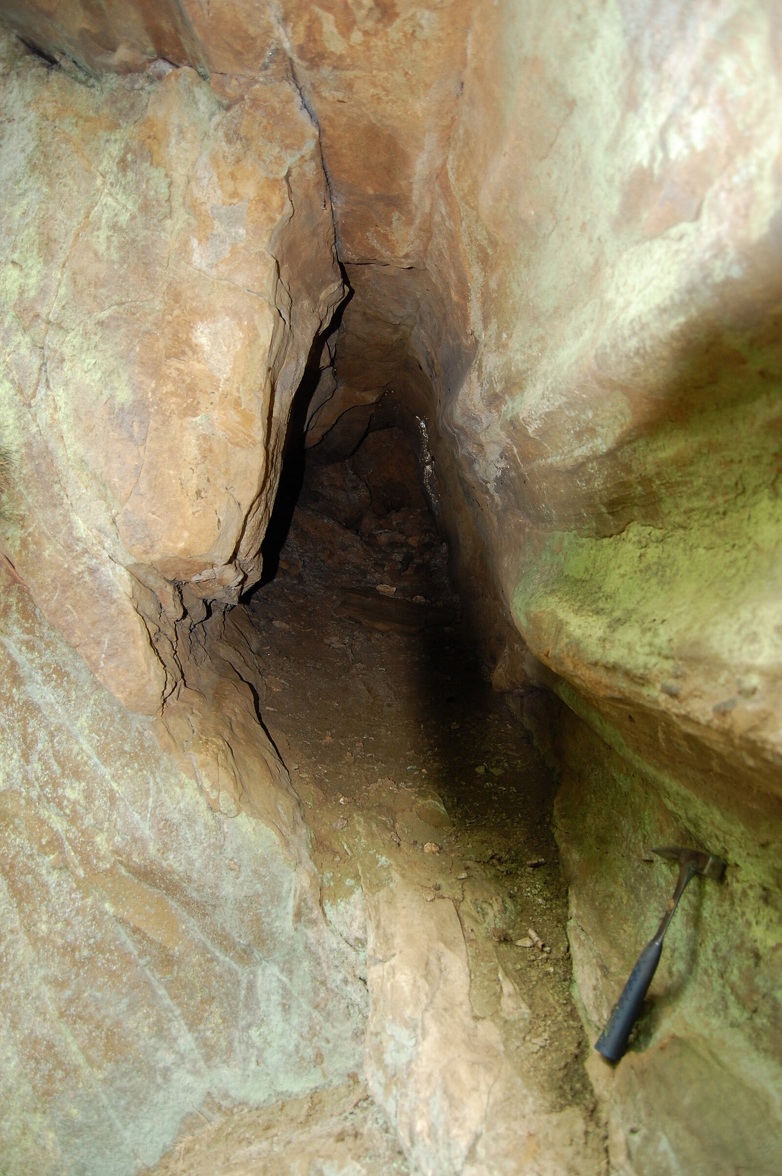 Hohlraum in Gestein mit Hammer als Größenvergleich