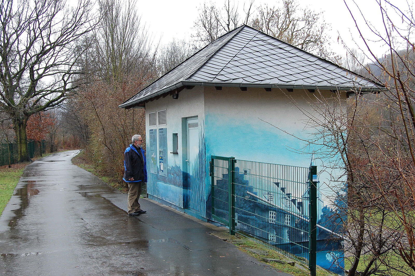 Kleines Haus mit blauer Zeichung auf den Wänden an Straße mit Mann davor
