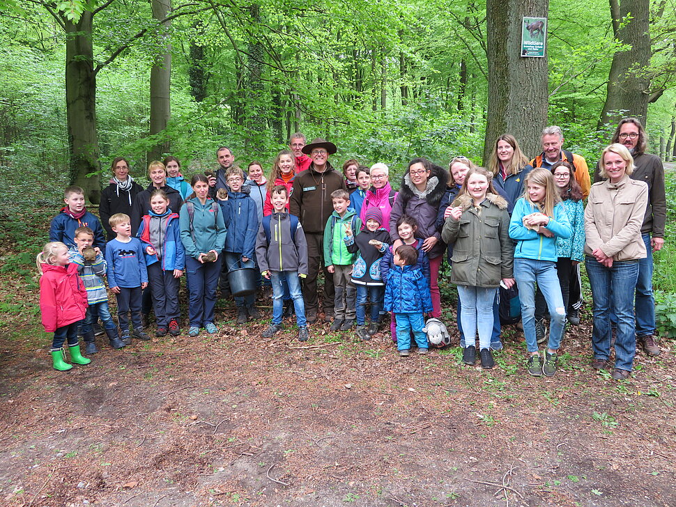 Große Gruppe mit Familien, die Fossilien präsentieren und Ranger. 