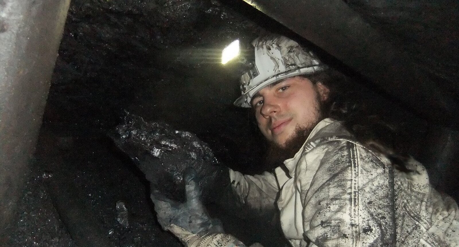 Mann mit Grubenlampe und Steinkohlebrocken in Bergwerk.