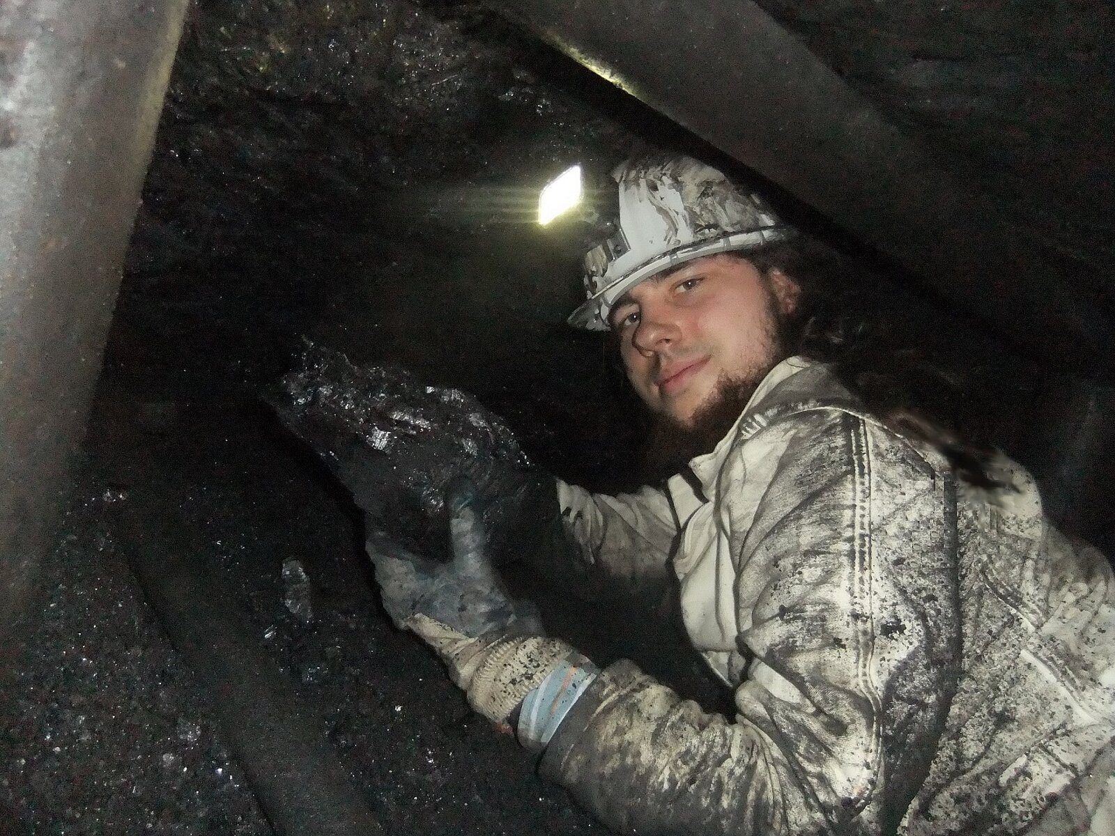 Mann mit Grubenlampe und Steinkohlebrocken in Bergwerk.