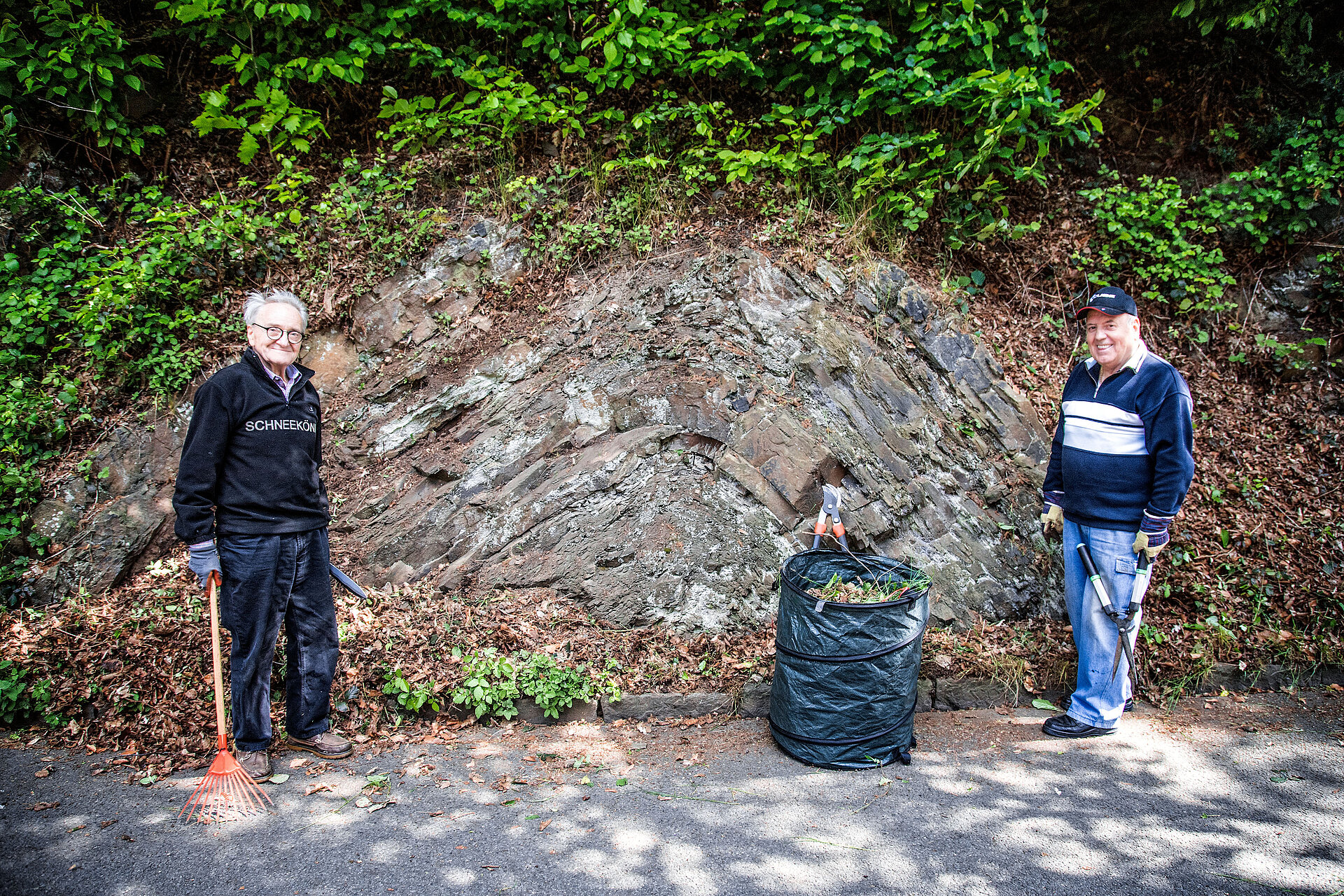 2 Männer mit Grünschnitt vor Felswand