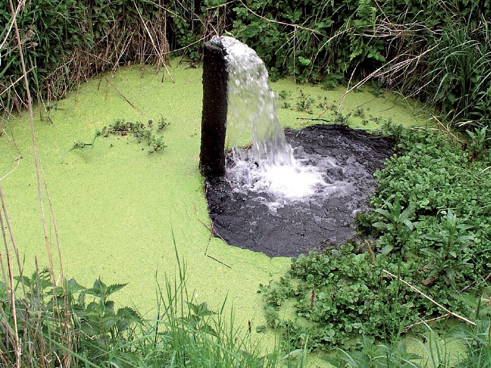 Waaserloch mit Rohr, aus dem Wasser sprudelt