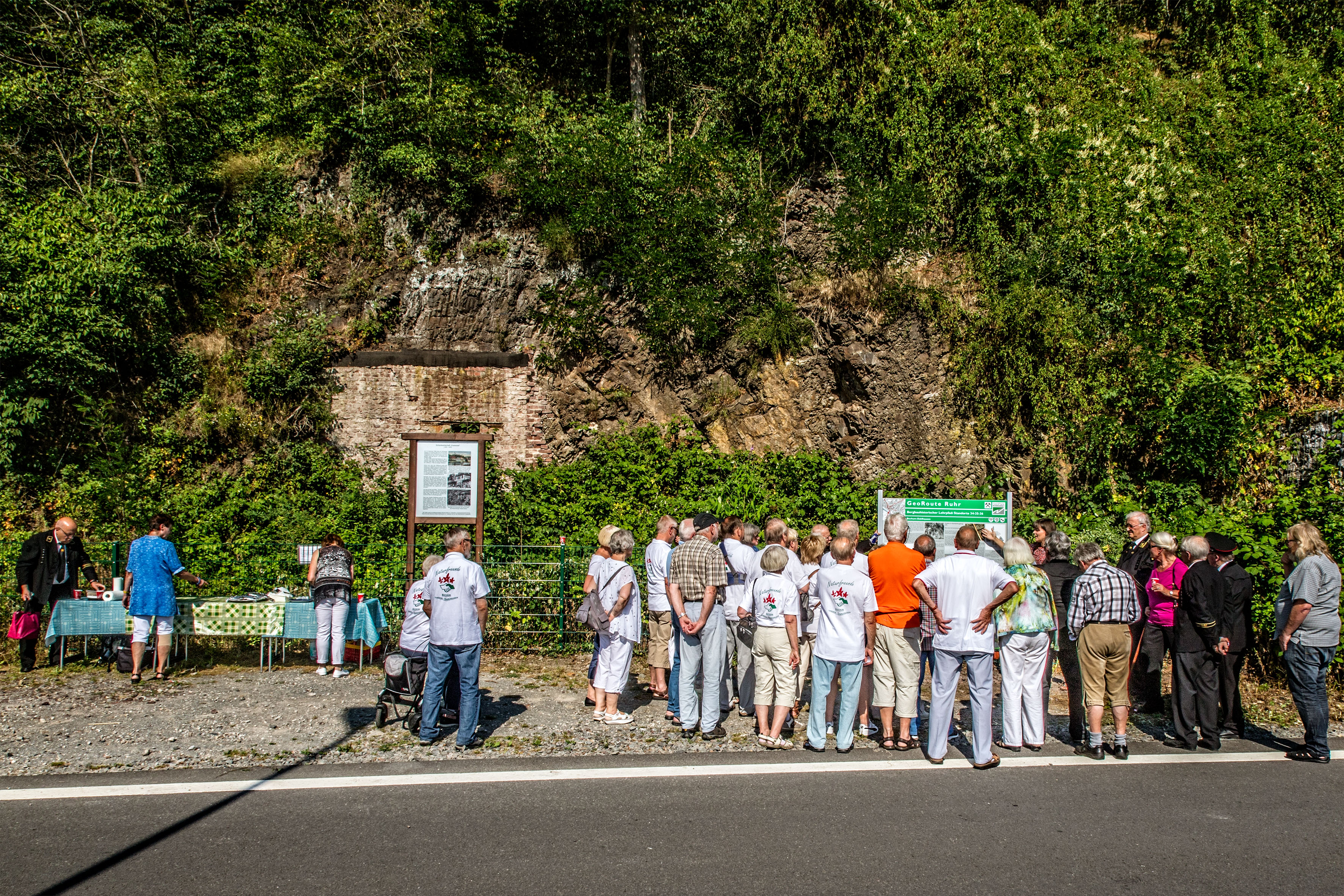 Aufschluss mit Infotafeln und Gruppe von Menschen