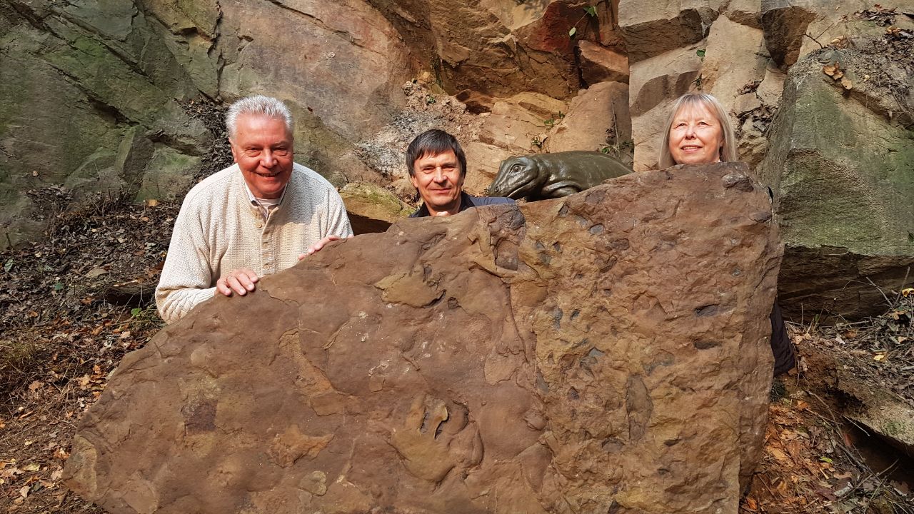 Zwei Männer und eine Frau hinter Platte mit Fährtenfossil