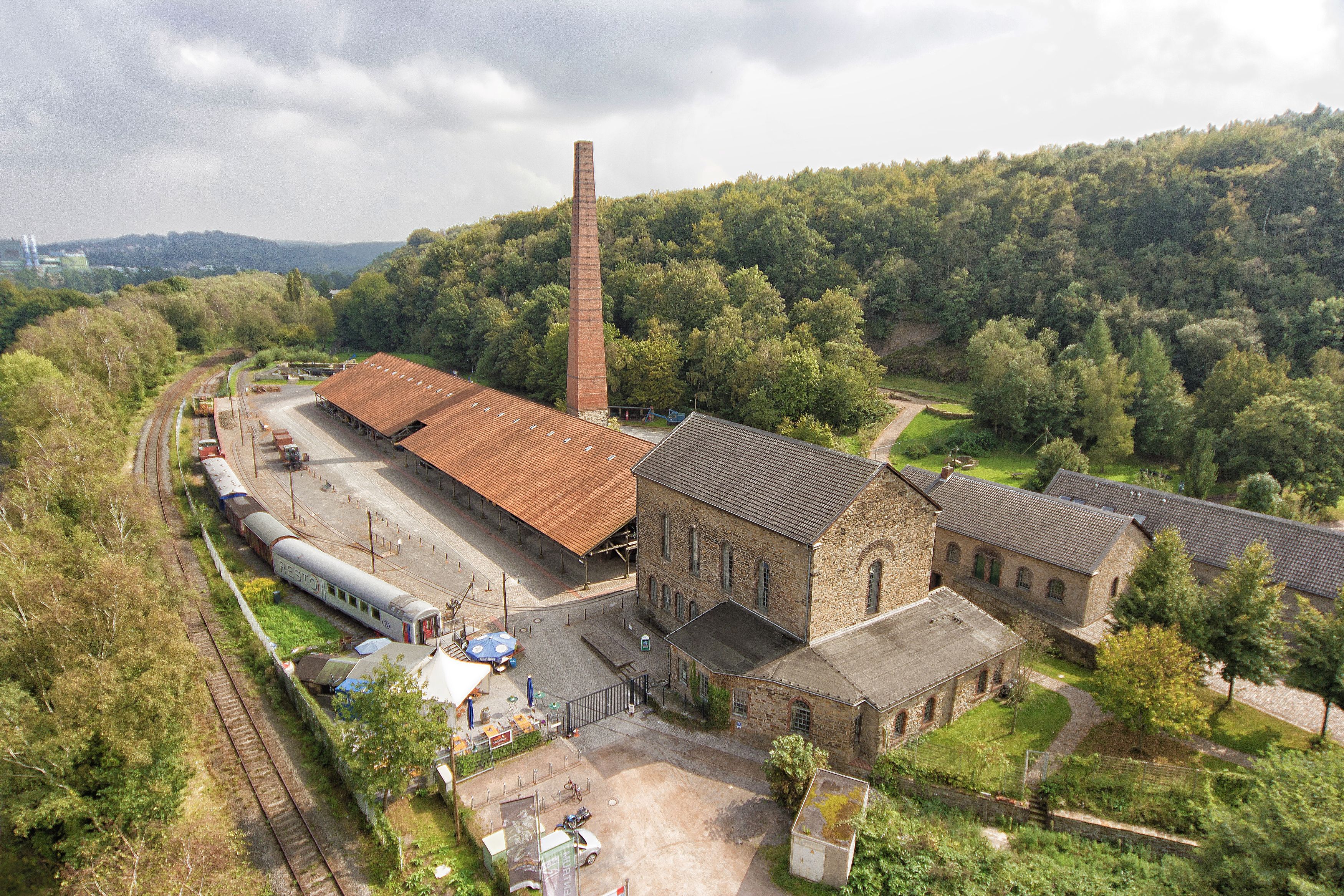 Luftbild mit historischen Gebäuden und hohem Kamin