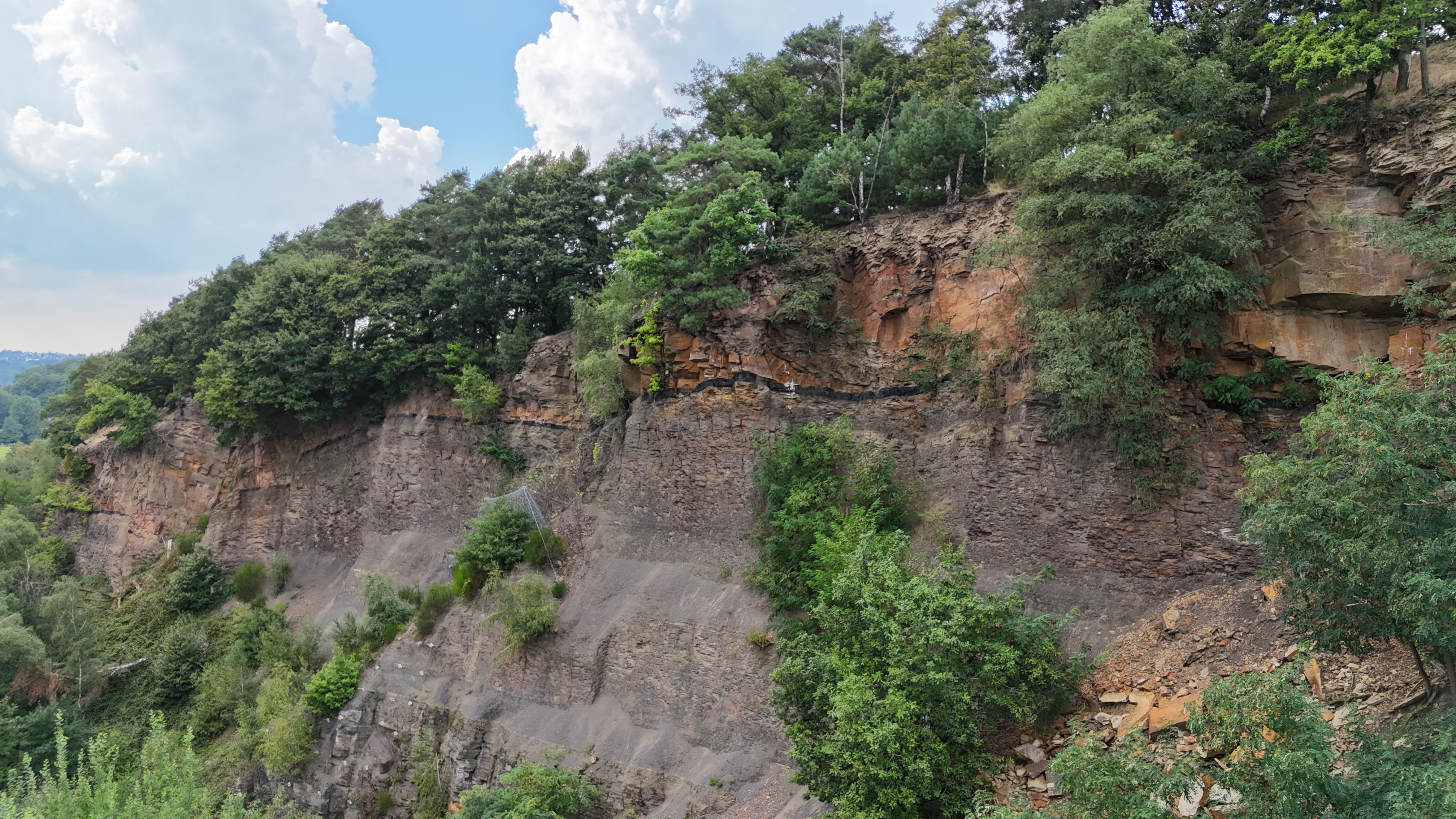 Felswand mit Felssicherung und Stolleneingang mit Eisengitter