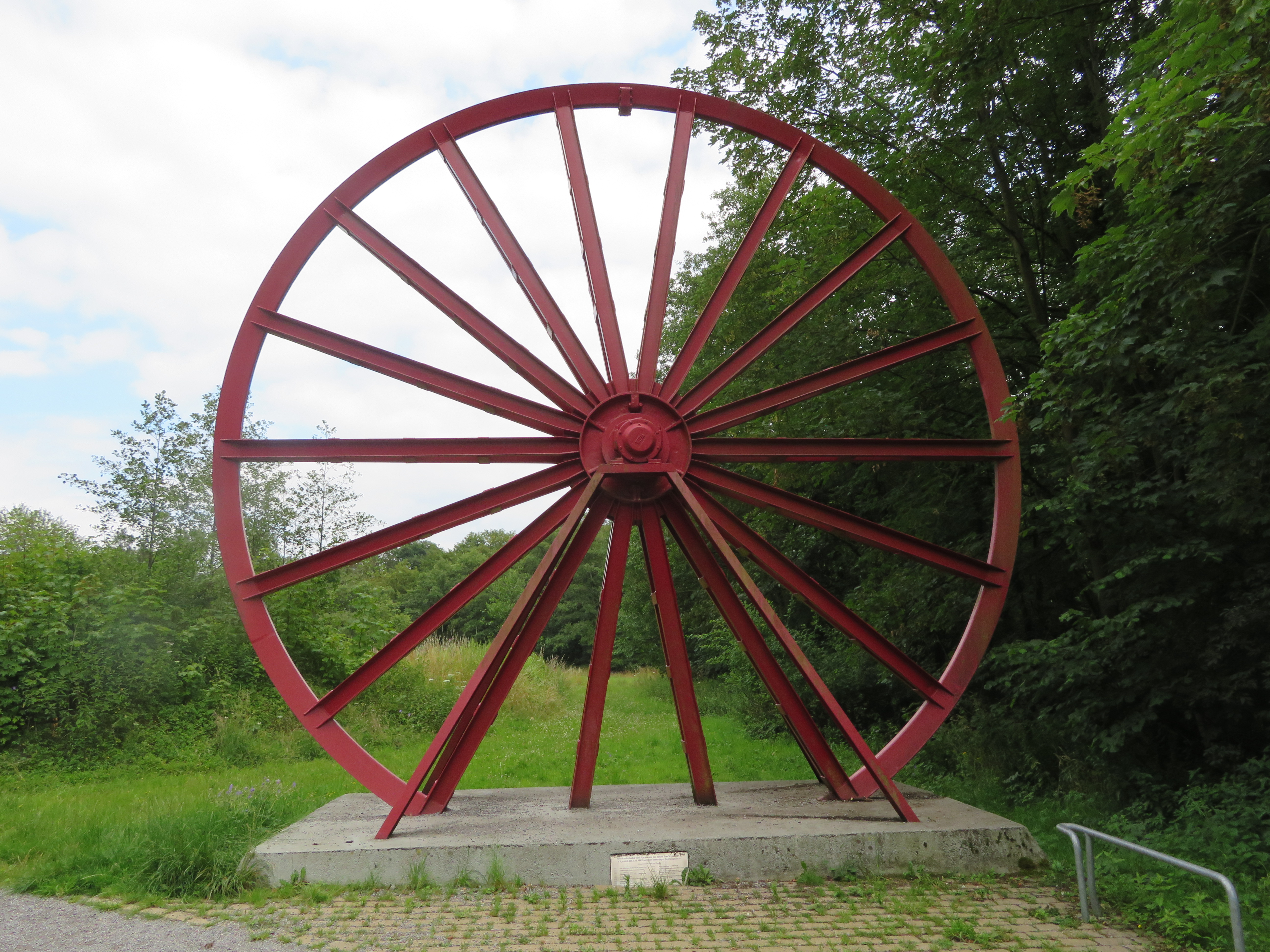 großes rotes Stahlrad auf Betonsockel