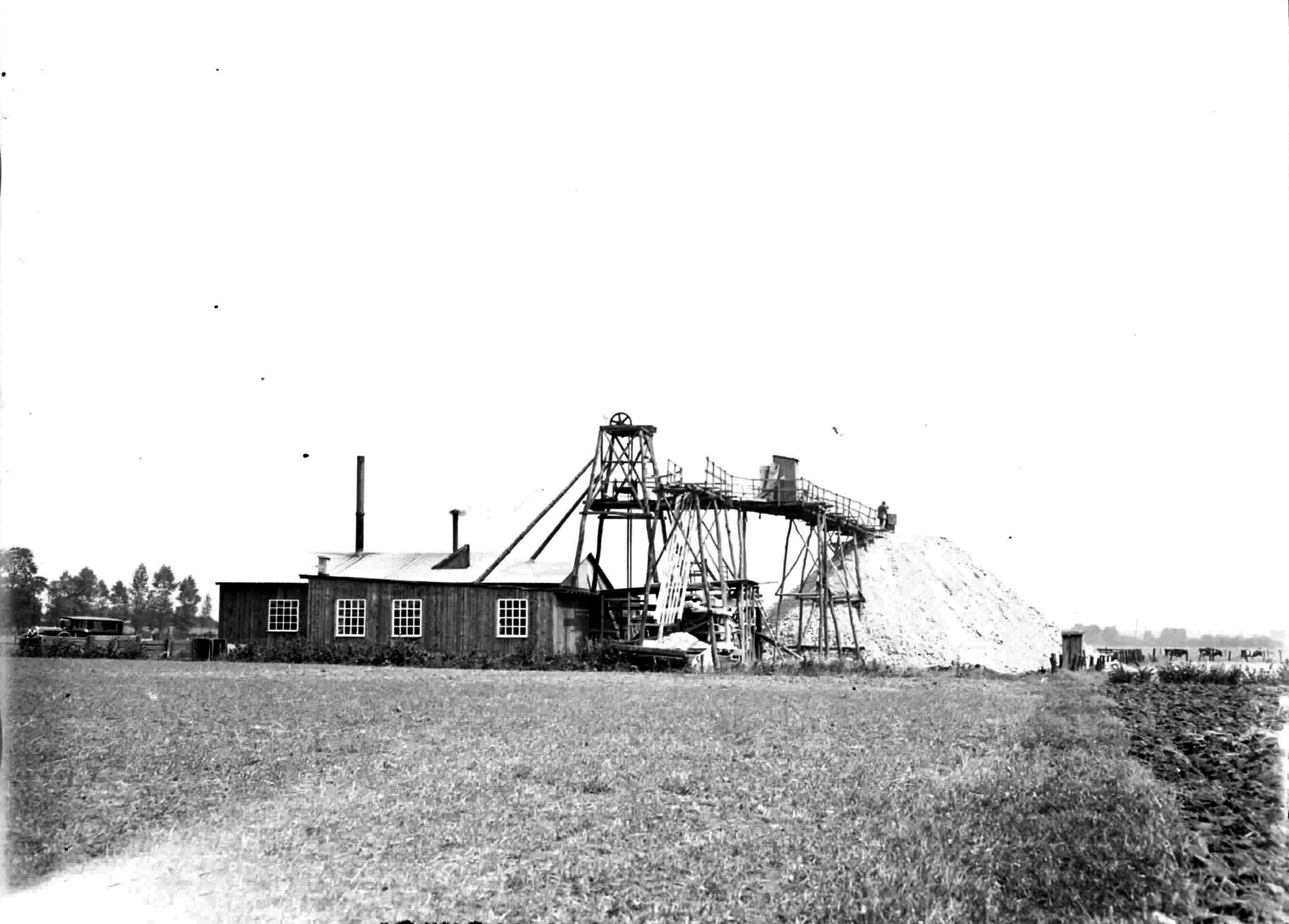 Historisches Foto mit Holzgebäude, Fördertum aus Holz und einem Berg aus weißem Gestein